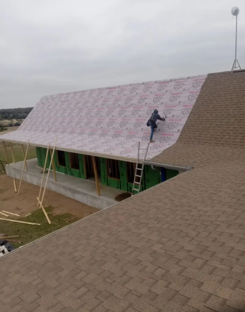 Worker preparing underlayment for a metal roof installation in Hallsville